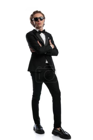 Foto de Atractivo hombre de negocios posando con la barbilla hacia arriba y los brazos cruzados, con un traje formal sobre fondo blanco estudio - Imagen libre de derechos