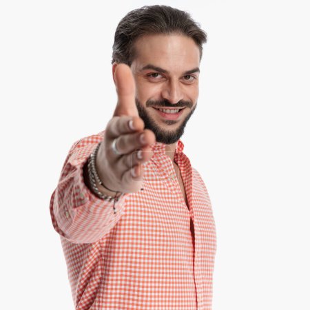 Téléchargez les photos : Beau jeune homme en chemise à carreaux pointant la main vers l'avant et souriant devant fond blanc en studio - en image libre de droit