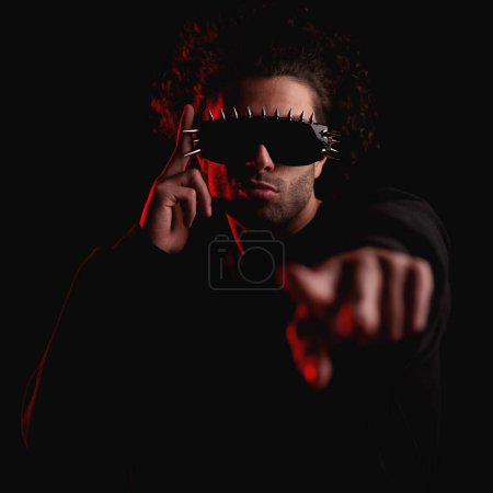 Photo for Cool young man with curly hair wearing sunglasses and making hand gesture, pointing finger forward while touching and fixing glasses with the other hand - Royalty Free Image