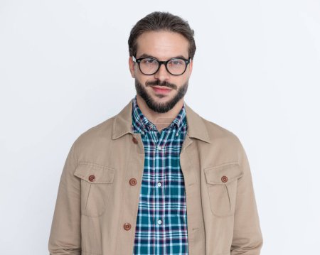 Photo for Attractive young man with glasses wearing jacket, smiling and posing in front of grey background in studio - Royalty Free Image