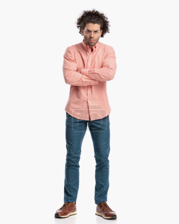 Photo for Upset young man with glasses wearing plaid shirt and crossing arms while waiting for answers in front of white background in studio - Royalty Free Image