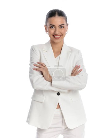 Photo for Fashion young woman in white suit with bun hair crossing arms and smiling while confidently posing in front of white background - Royalty Free Image
