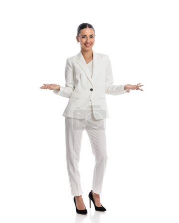 Photo for Proud elegant businesswoman in white suit being happy, smiling, opening arms and showing in front of white background - Royalty Free Image