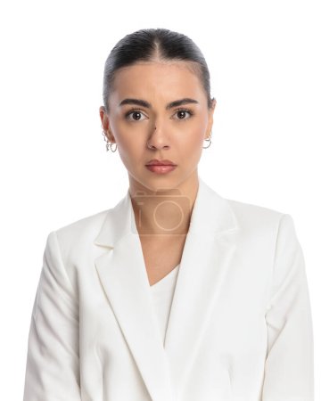 Téléchargez les photos : Effrayée jeune femme en costume blanc ayant peur et regardant vers l'avant devant fond blanc - en image libre de droit