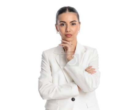 Téléchargez les photos : Portrait d'une jeune femme d'affaires confiante en costume blanc pliant les bras et pensant devant un fond blanc - en image libre de droit