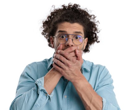 Photo for Closeup of shocked casual man covering his mouth with hands on white background - Royalty Free Image