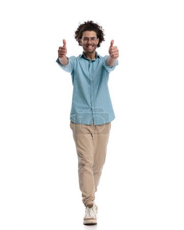 Photo for Smiling casual man making ok sign while stepping forward on white background - Royalty Free Image