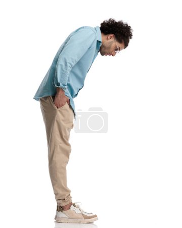 Photo for Side view of curious casual man looking down while waiting in line on white background - Royalty Free Image