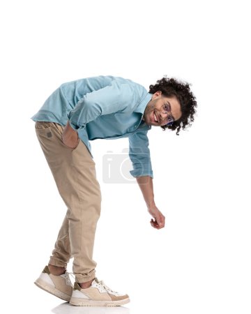 Foto de Vista lateral del alegre hombre casual levantando algo desde el suelo sobre un fondo aislado - Imagen libre de derechos