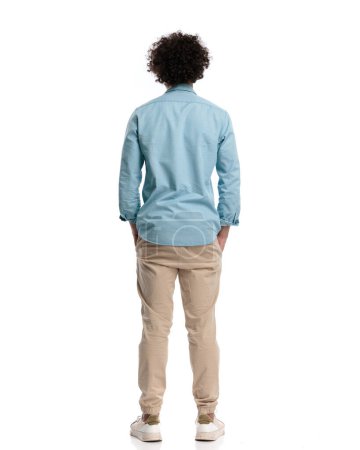 Photo for Back view of relaxed young man with curly long hair standing on isolated background - Royalty Free Image