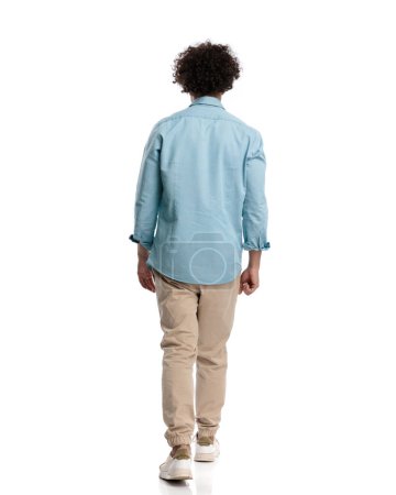 Photo for Behind of young casual man stepping on white background - Royalty Free Image