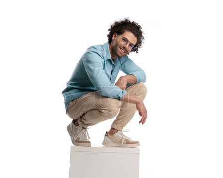 Photo for Casual man wearing glasses and blue shirt leaning forward while standing on crate on isolated background - Royalty Free Image