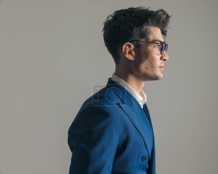 Téléchargez les photos : Vue de côté portrait de mode sexy homme avec des lunettes regardant vers le côté et posant devant fond blanc - en image libre de droit