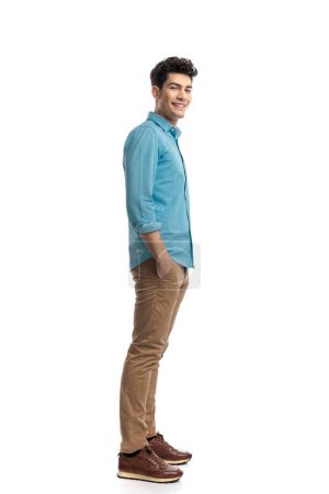 Photo for Happy casual man wearing blue shirt and jeans waiting in line while holding pockets - Royalty Free Image
