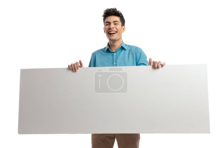 Photo for Close up of joyful casual man holding empty advertisement and laughing on white background - Royalty Free Image