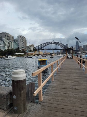 Téléchargez les photos : L'estran portuaire de Sydney se dresse contre le célèbre pont du port de Sydney par temps nuageux - en image libre de droit