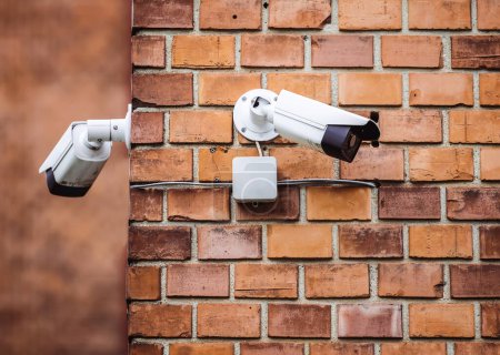 Group of security cameras on red brick wall