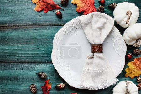 Photo for Flat lay of a white plate with napkin. Place setting over a rustic wood table with colorful autumn leaves. Table top view. - Royalty Free Image