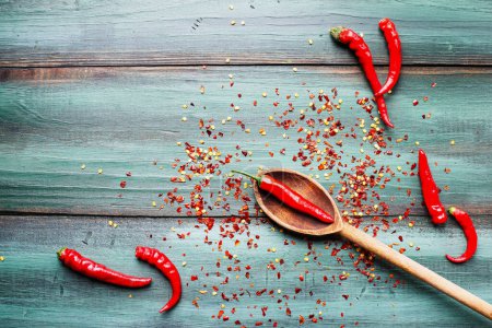Photo for Red hot spicy cayenne peppers, both fresh and dried seeds, in wooden spoon. Flat lay over rustic background. - Royalty Free Image