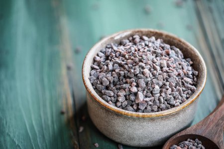 Photo for Bowl of Himalayan Black Salt, or Kala Namak, with a wooden spoon. Selective focus with blurred background and foreground. - Royalty Free Image