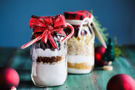 Photo for Variety of gifts of chocolate chip cookie dough and macadamia nut recipe mixture of ingredients for baking cookies for Christmas.  Tied with a red ribbon and candy canes. Selective focus with blurred background. - Royalty Free Image