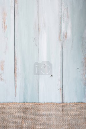 Photo for Blue and white rustic wooden background with burlap ribbon going across the bottom of the table. Overhead top view. - Royalty Free Image