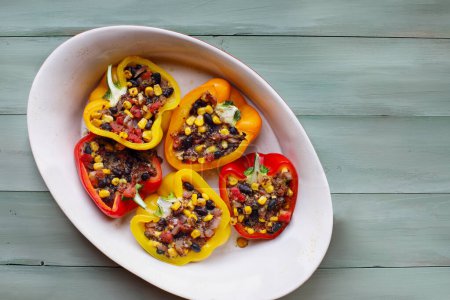 Photo for Overhead view of vegan stuffed peppers. These bell peppers have been filled with a southwestern mix of quinoa, corn, black beans, tomatoes and herbs. High in fiber and delicious. Top view. - Royalty Free Image