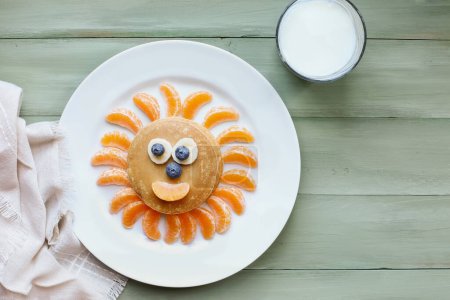 Photo for Fun, colorful creative pancake sun for children with banana and blueberry eyes and oranges for sunbeams and smile to encourage kids to eat healthy foods. - Royalty Free Image