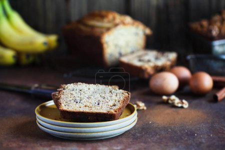 Photo for Slices of fresh homemade banana bread on a stack of saucers with ingredients nearby. Selective focus with blurred foreground and background. - Royalty Free Image