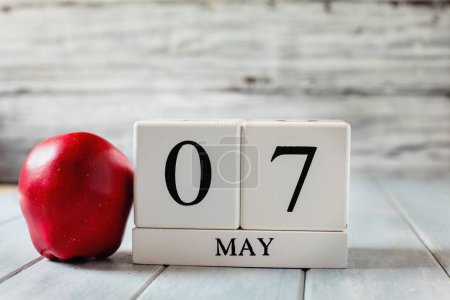 Photo for White wood calendar blocks with the date May 7th and a red apple for National Teacher Appreciation Day. - Royalty Free Image