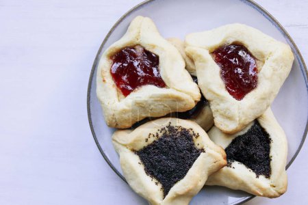 Photo for Variety of traditional hamantaschen cookies filled with mohn paste (poppy seed paste) and plum jam for the Jewish festival of Purim. Table top view. - Royalty Free Image
