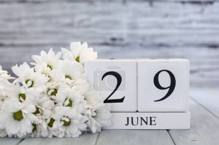 Photo for White wood calendar blocks with the date June 29th and white daisies. Selective focus with blurred background. - Royalty Free Image