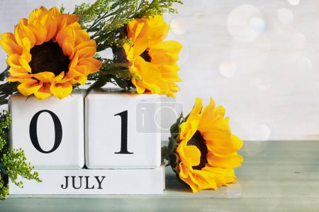 Photo for Canada Day. White wood calendar blocks with the date July 1st and beautiful sunflower bouquet with bokeh. Selective focus with blurred background. - Royalty Free Image