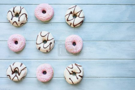 Photo for Flatlay of frosted vanilla donuts with chocolate swirls and strawberry pink doughnuts with coconut flakes with copy space. Overhead table top view. Flatlay background. - Royalty Free Image