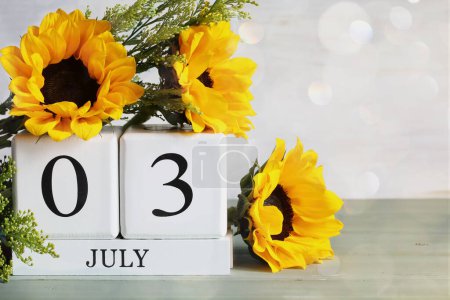 Photo for National Plastic Bag Free Day. White wood calendar blocks with the date July 3rd and beautiful sunflower bouquet with bokeh. Selective focus with blurred background. - Royalty Free Image