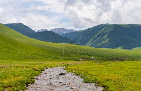 Foto de Hermosa naturaleza de Kazajstán en la meseta de Assy en verano. Río de montaña, colinas verdes y yurtas blancas. - Imagen libre de derechos
