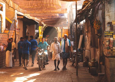 Photo for Gokarna, India - February 21, 2023 - Morning in Gokarna, people walking along a street illuminated by sunlight. Karnataka state, India - Royalty Free Image