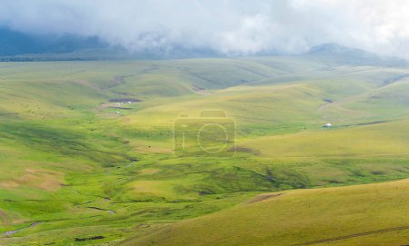 Sommerlandschaft mit grünen Hügeln und bewölktem Himmel. Plateau Assy, Kasachstan.