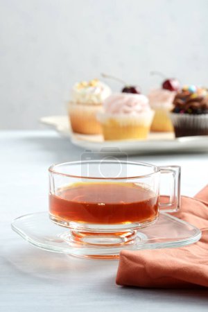 Foto de Primer plano taza de té con cupcakes en el fondo - Imagen libre de derechos