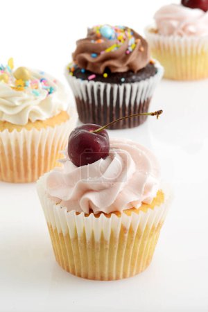 Foto de Primer plano crema de mantequilla de cereza cupcake con surtidos cupcakes en el fondo - Imagen libre de derechos