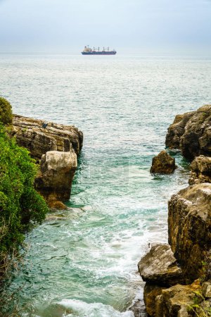 Photo for A cargo ship is sailing out of Porgugal as seen from the Cascais coast - Royalty Free Image