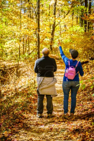 Foto de Senior couple is hiking in the woods in North Carolina in fall - Imagen libre de derechos