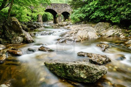 Photo for Long exposure image of West Fork Pigeon River under Tripple Arch Bridge near Maggie Valley, North Carolina. - Royalty Free Image