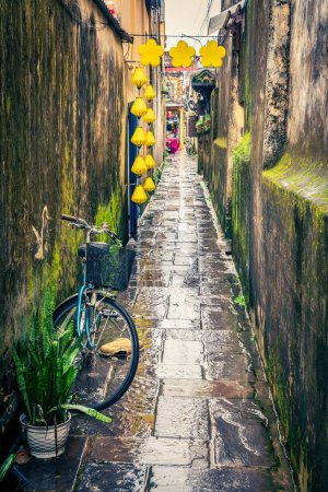 Téléchargez les photos : Ruelle étroite dans la vieille ville de Hoi An, Vietnam par un jour de pluie - en image libre de droit