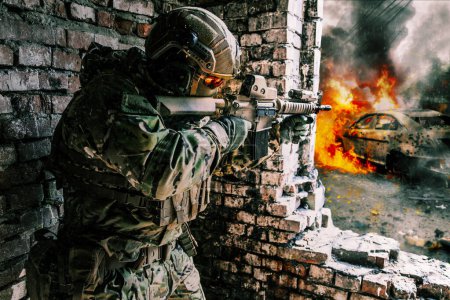 Foto de A soldier in action in a ruined building, danger of modern warfare. Fighting in destroyed building, engaged in combat with an unseen enemy. Armed with a firearm and other equipment. Concept of urban - Imagen libre de derechos