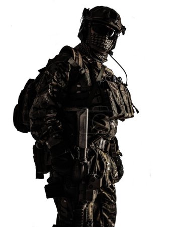 Foto de Disparo de ángulo bajo de un soldado del ejército militar en camuflaje con rifle de asalto. Estudio plano, contraste oscuro, recortado, desaturado, aislado sobre fondo blanco - Imagen libre de derechos