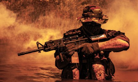 A bearded soldier performs a surveillance task in the water, walking through a swamp, surrounded by mist fog, rifle at the ready for imminent threats, colorized toned shot