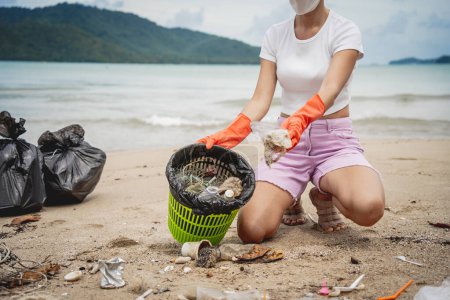 Foto de A female ecologist volunteer cleans the beach on the seashore from plastic and other waste. - Imagen libre de derechos