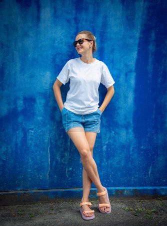 Photo for Female model wearing white blank t-shirt on the background of an blue wall - Royalty Free Image