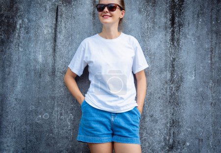 Weibliches Model trägt weißes T-Shirt auf dem Hintergrund einer grau zerkratzten Wand